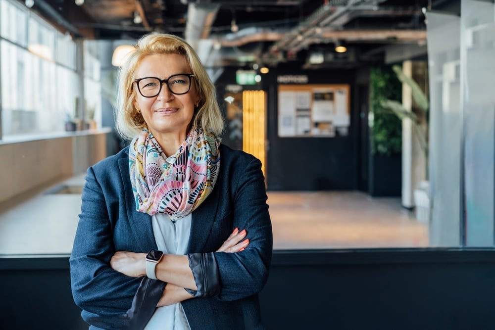 Confident woman standing with arms crossed in a modern office building, illustrating the professional appearance and role of a UK company director